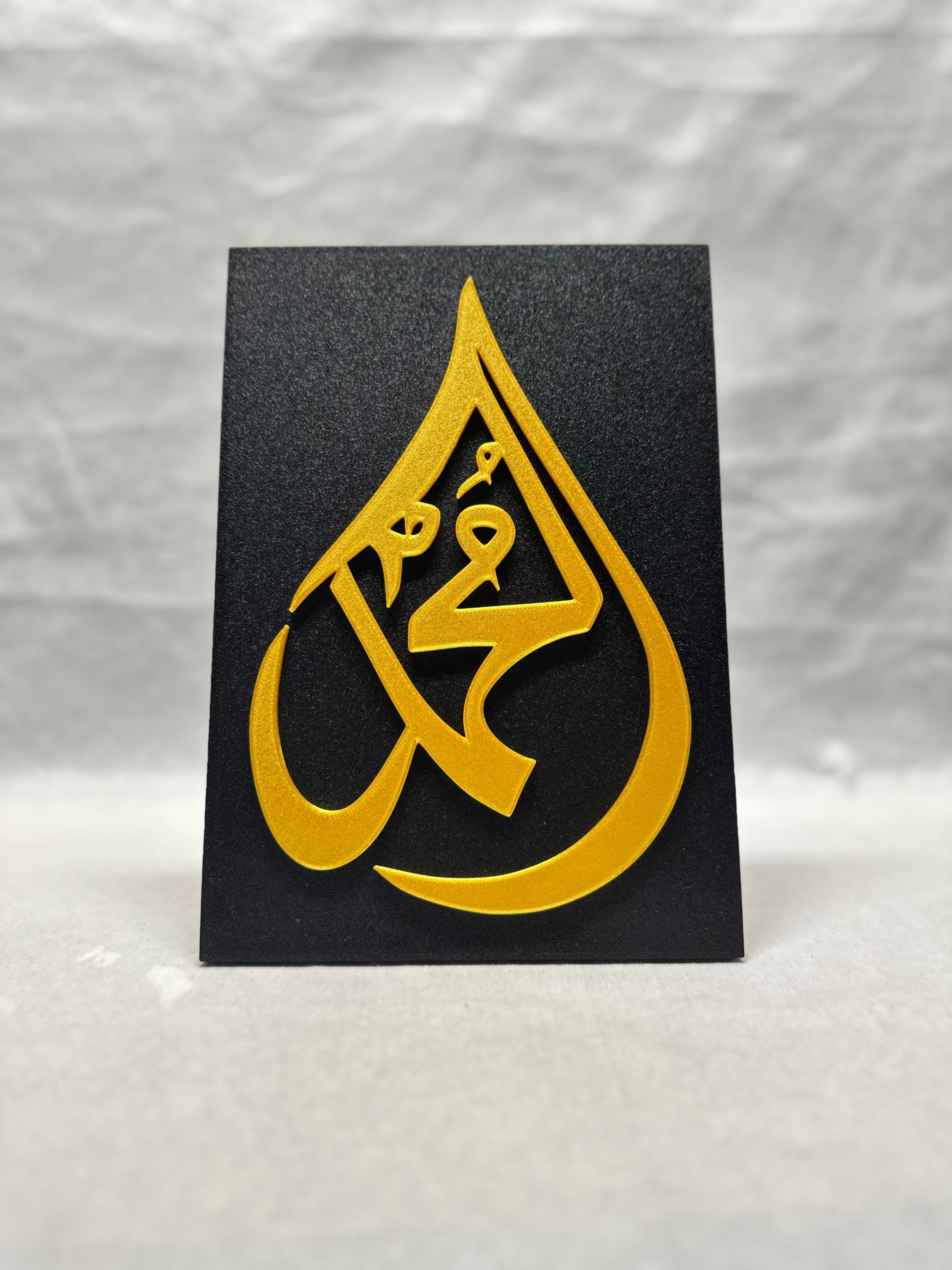 Gold raised Arabic calligraphy of Muhammad on black textured panel