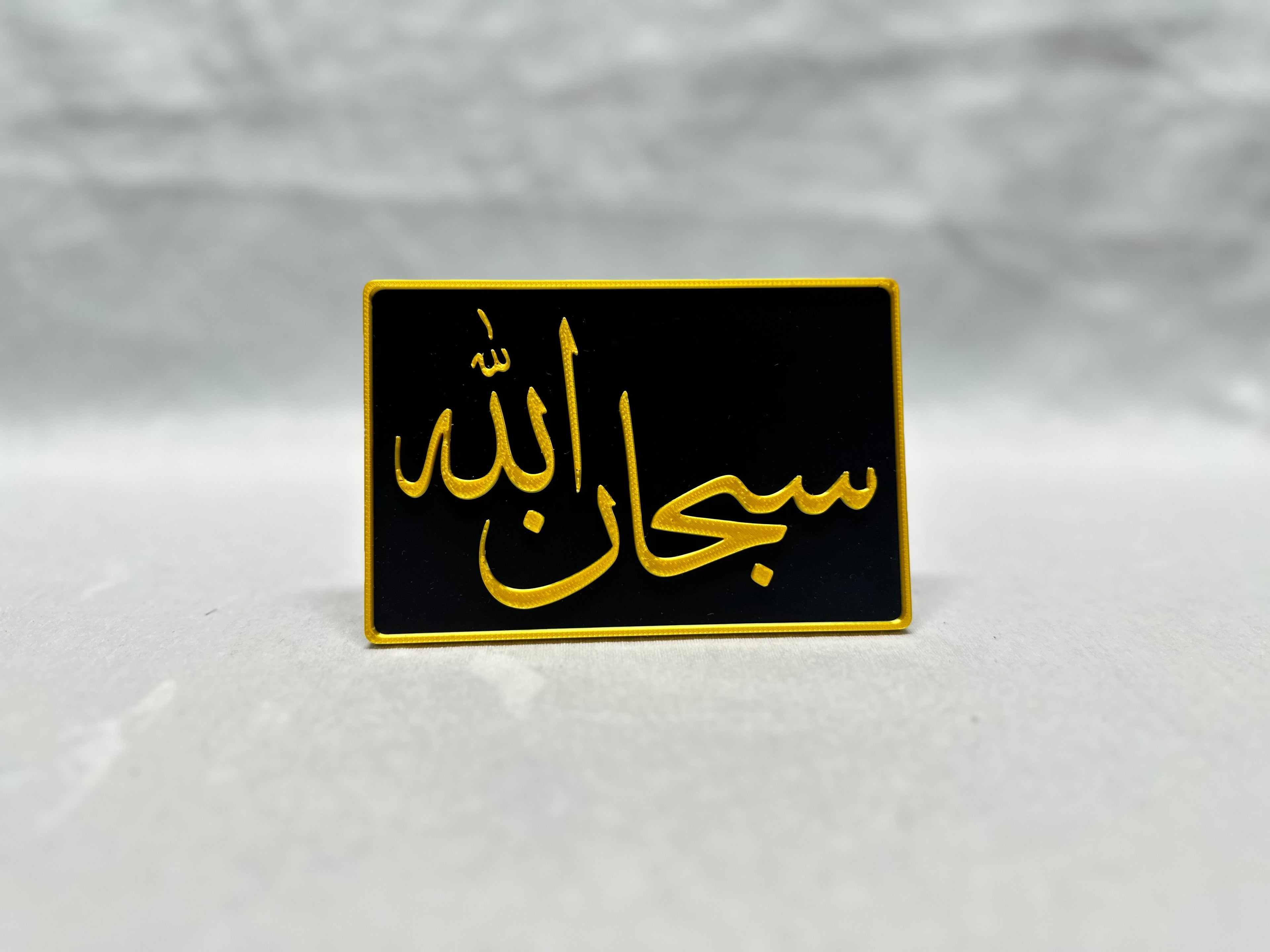 Gold raised Arabic calligraphy of Subhanallah on black panel