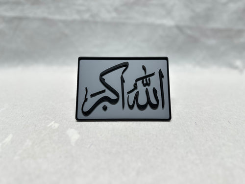 Black raised Arabic calligraphy of Allah Akbar on gray panel