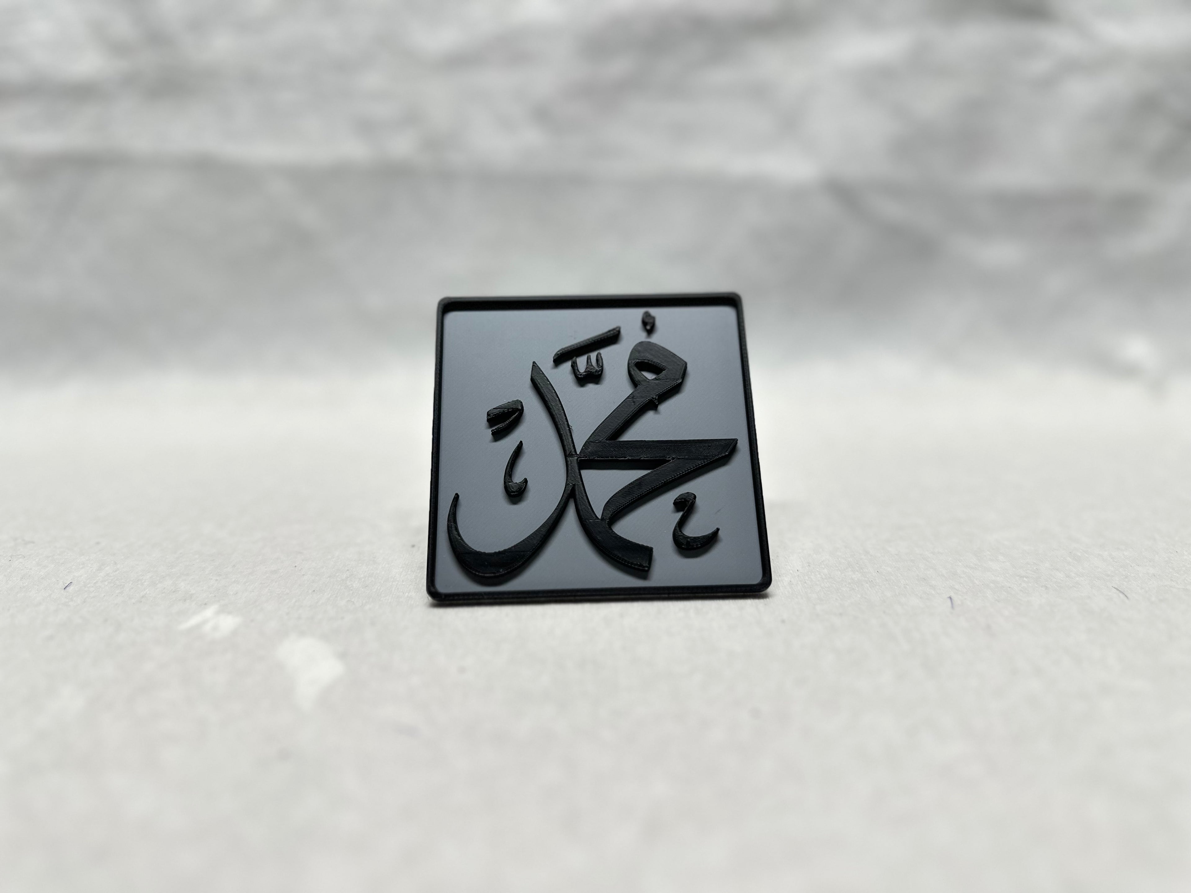 Black raised Arabic calligraphy of Muhammad on gray panel