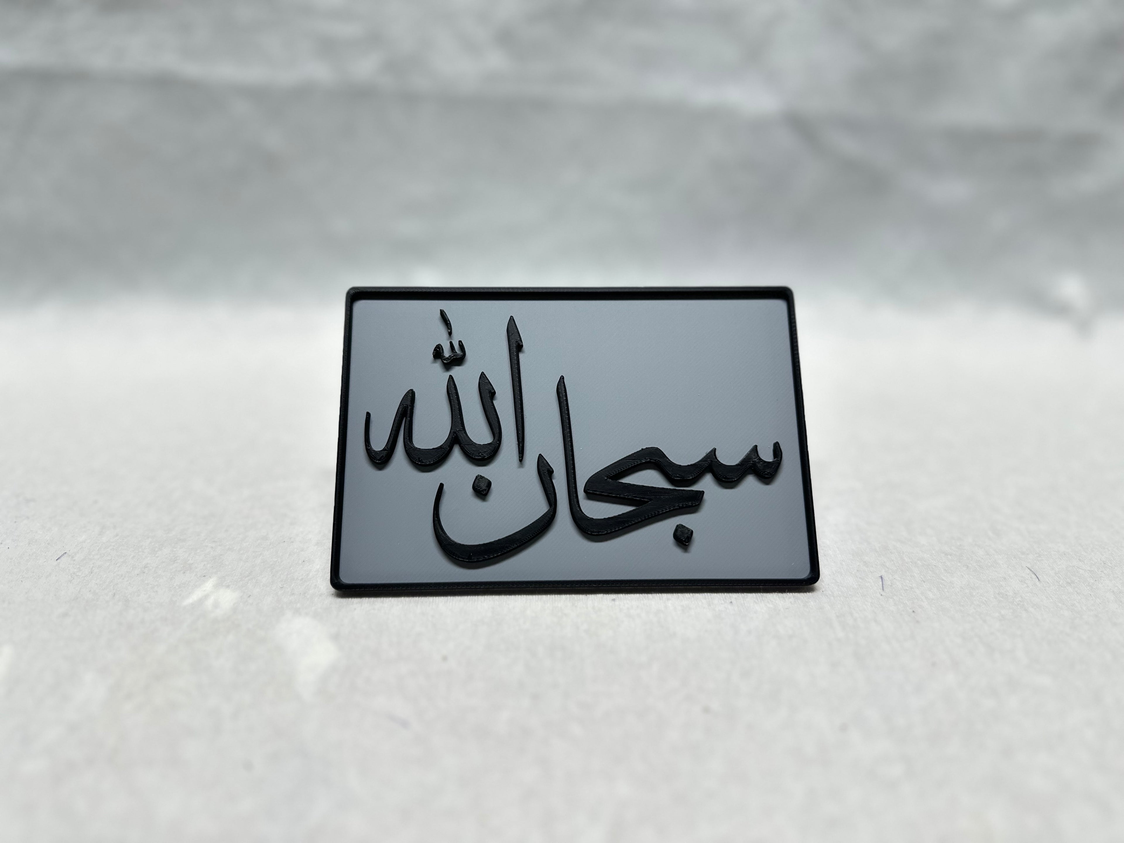 Black raised Arabic calligraphy of Subhanallah on gray panel